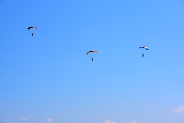 Fototapeta na wymiar three paratroopers descend against a blue sky