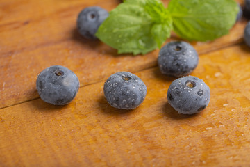 Juicy and fresh blueberries with green mint leaves on a wooden table. Blueberries on wooden background.