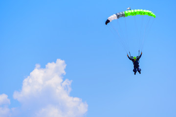parachutist descends into the blue sky on a sunny day