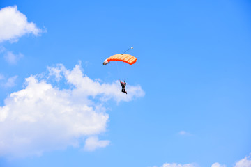 parachutist descends into the blue sky on a sunny day