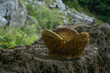 Traditional unleavened homemade bread in wooden basket on the rock in high mountain