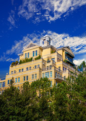 Yellow Stucco Hotel Rising out of Trees Into Blue Sky