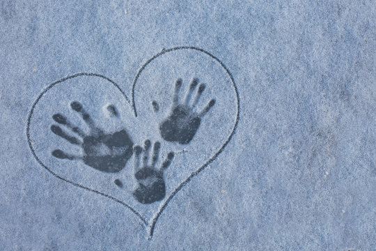 fingerprint on the snow. Three tracks from hands on the snow in painted heart. Love in the winter. Mom, Dad and baby.