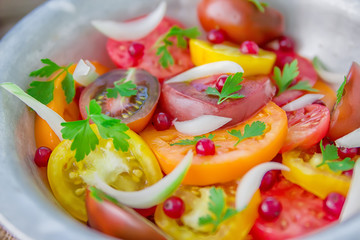 Tasty summer salad of sliced fresh colorful tomatoes, chopped red onion with white currant berries, olive oil,  and parsley. Healthy meal