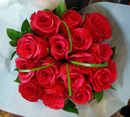 Bouquet of red roses with green ribbon accent.