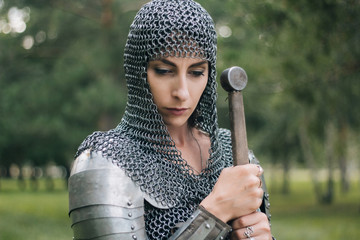 Medieval girl warrior, in a chain mail hood with a sword in his hand. A woman in European armor. Viking. Fantasy