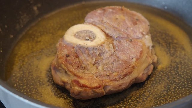 veal slice with marrowbone breaded in flour is fried in a pan