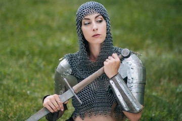 Medieval girl warrior, in a chain mail hood with a sword in his hand. A woman in European armor....