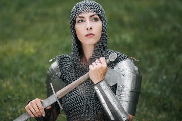 Medieval girl warrior, in a chain mail hood with a sword in his hand. A woman in European armor....