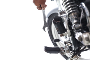 Cropped view of Mechanic using a wrench on a motorcycle on white background