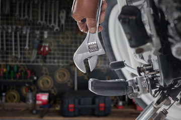 Cropped view of Mechanic using a wrench on a motorcycle