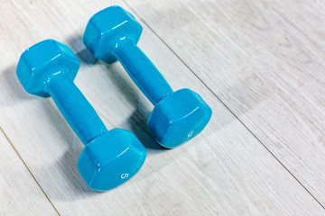 Blue modern dumbbells on a wooden floor