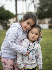 Happy funny girl twins sisters hugging and laughing