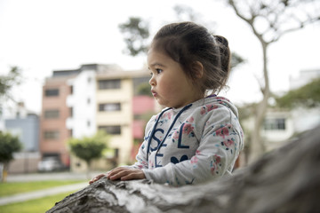 Little girl hugging a tree, looking up