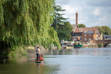 stratford upon Avon Warwickshire England UK August 23rd punt under a willow tree with beautiful buildings and bridge in the background during English summer