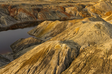 a pond - a lake or a river - with red water in a canyon among deserted sandy hills