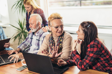 Young volunteers help senior people on the computer. Young people giving senior people introduction to internet
