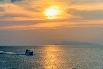 Fototapeta premium Łódź motorowa do wędkowania na morzu wracająca na brzeg podczas zachodu słońca pośród natury i pięknego nieba.