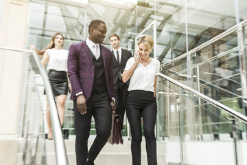 Fototapeta premium young businessmen go down the stairs and communicate. African American man and European woman