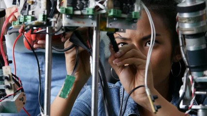 Female engineer fixing robot in workshop. Assistance help female engineer to fix robot. 4k resolution. - Powered by Adobe
