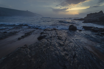 Sunset in Tagle beach. panoramic view of nice colorful huge cliff and sea on the back. Cantabria. Spain.