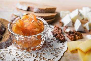 Small dish with apple jam cheese bread and nuts on a wooden board, selective focus