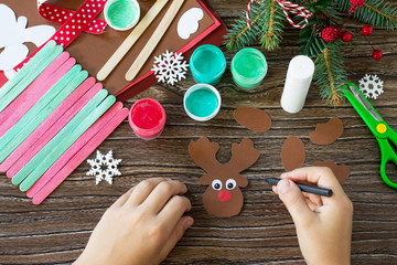 The child draws details Santa and Reindeer stick gift. Handmade. Project of children's creativity, handicrafts, crafts for kids.