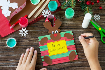 The child draws details Santa and Reindeer stick gift. Handmade. Project of children's creativity,...