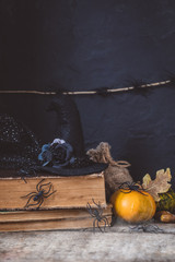 Halloween holiday background with lantern, spiders, old books, black witchhat