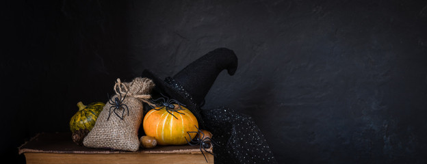 Halloween holiday background with pumpkin, spiders, old books, black witchhat