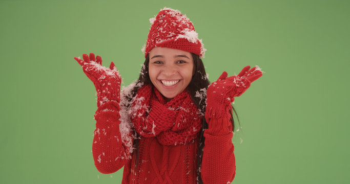 Cheerful latina girl in a red sweater covered in snow on green screen