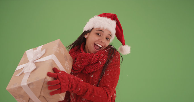 Happy hispanic girl in a christmas outfit holding a present on green screen