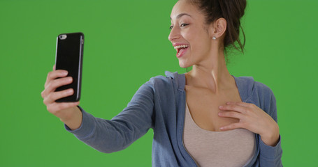 A Hispanic woman takes a selfie on green screen