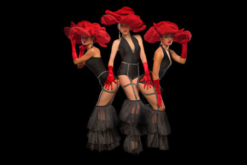 Three beautiful cabaret dancers in red hats isolated on black - obrazy, fototapety, plakaty