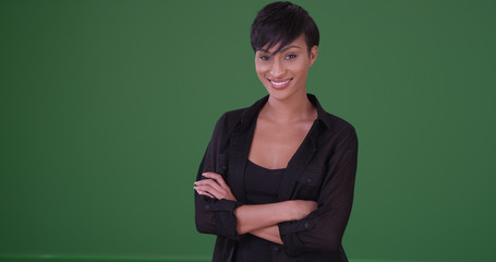 Young black woman in black attire smiling at the camera on green screen