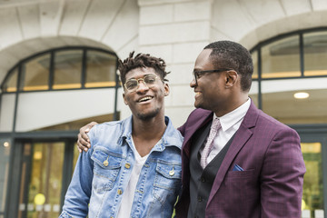 Fototapeta na wymiar two young and stylish African American men in the city smiling and talking. father and adult son relationship