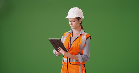 Young woman construction manager using tablet device on green screen - Powered by Adobe