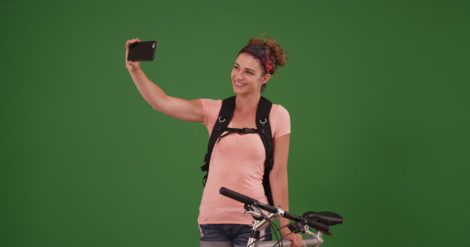 Millennial using smartphone to take selfie portrait on green screen