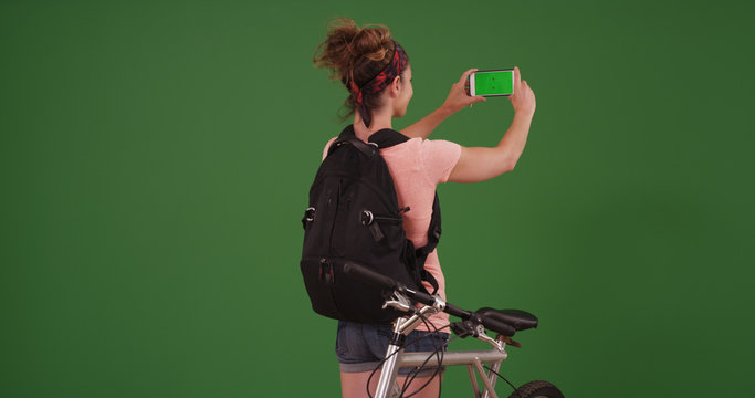 Woman in her 20s using smartphone to take photos on green screen