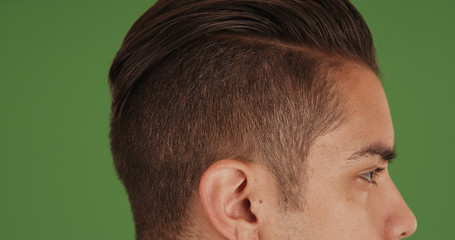 Fototapeta premium Side view of young millennial man with undercut standing on green screen