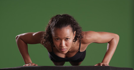 Mixed race millennial woman athlete doing push ups on green screen