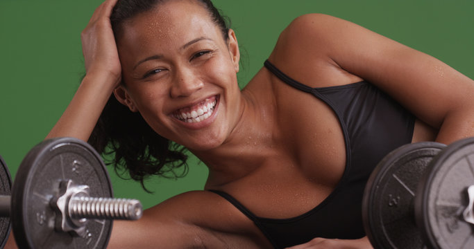 Happy mixed race woman laughing at camera after workout on green screen