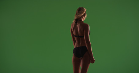 Rear view of attractive bikini woman facing away from camera on green screen