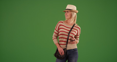 Stylish white female hipster with mobile device looking around on green screen