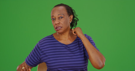 Black woman with rheumatism pointing to neck on green screen