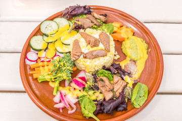Tuna and rice mixed salad on a white wood table and earthenware plate