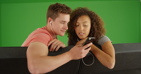 Young man and woman listening to music together on phone on green screen