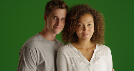 Cute millennial couple standing together smiling at camera on green screen