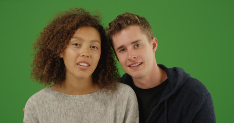 Portrait of casual millennial couple looking at camera on green screen