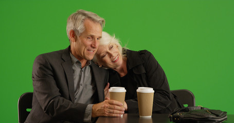 Senior couple out on date sitting at a cafe table with coffee on green screen